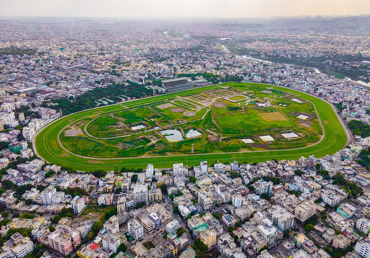 FairPlay Hyderabad Horse Racing: horses racing at a city course with the Charminar behind