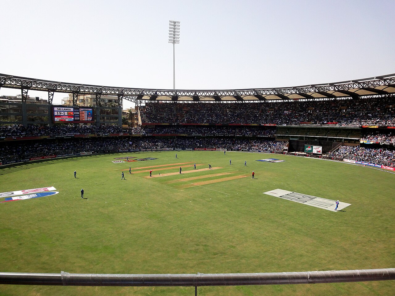 FairPlay Mumbai Cricket Stadium: a floodlit ground at dusk with the Mumbai skyline and sea link behind